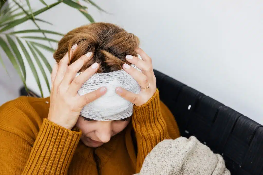 A woman holding bandaged head between her hands, representing wrongful denials of LTD insurance claims
