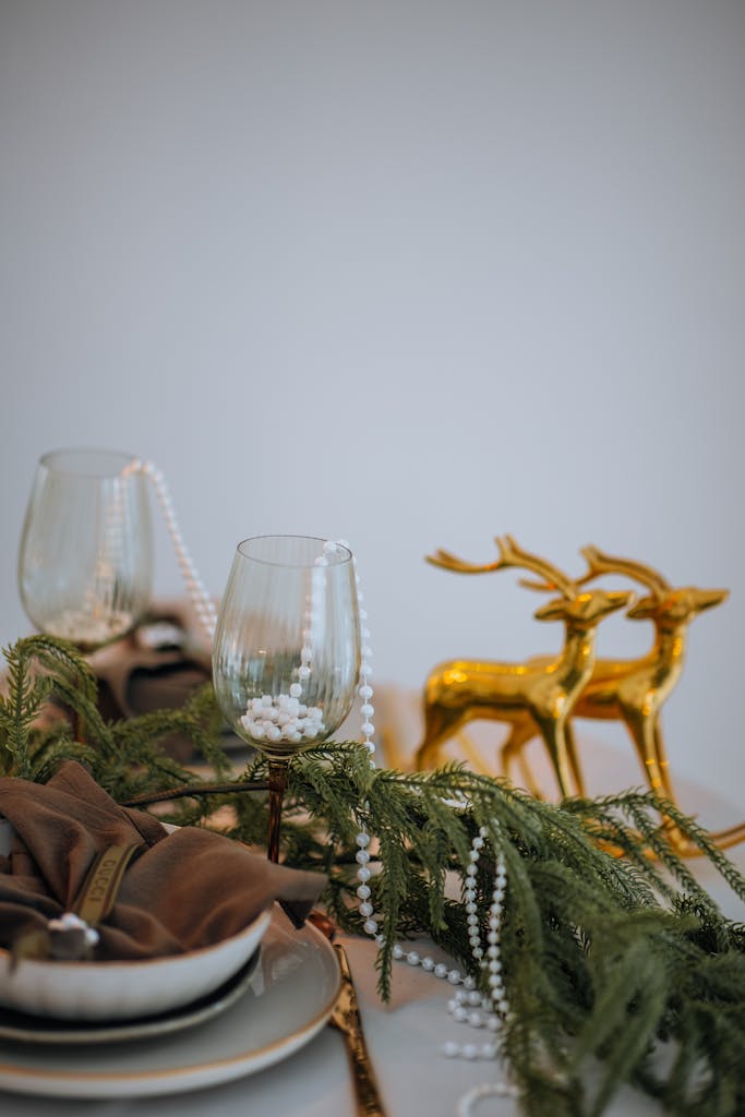 A stylish holiday table setup featuring gold reindeer, pearls, and greenery, perfect for festive gatherings.