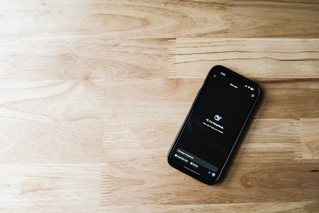 Top-down view of a smartphone displaying a chatbot interface on a light wooden surface.
